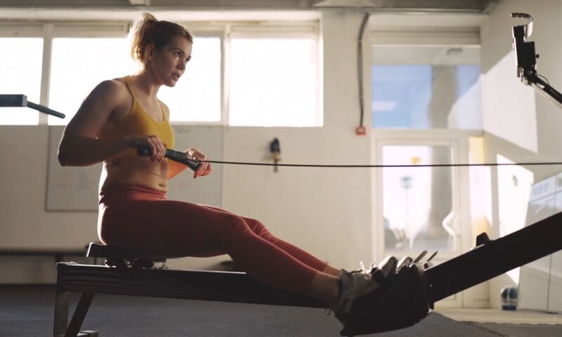 devojka u sportskoj odeči trenira uz pomoć sprave u teretani