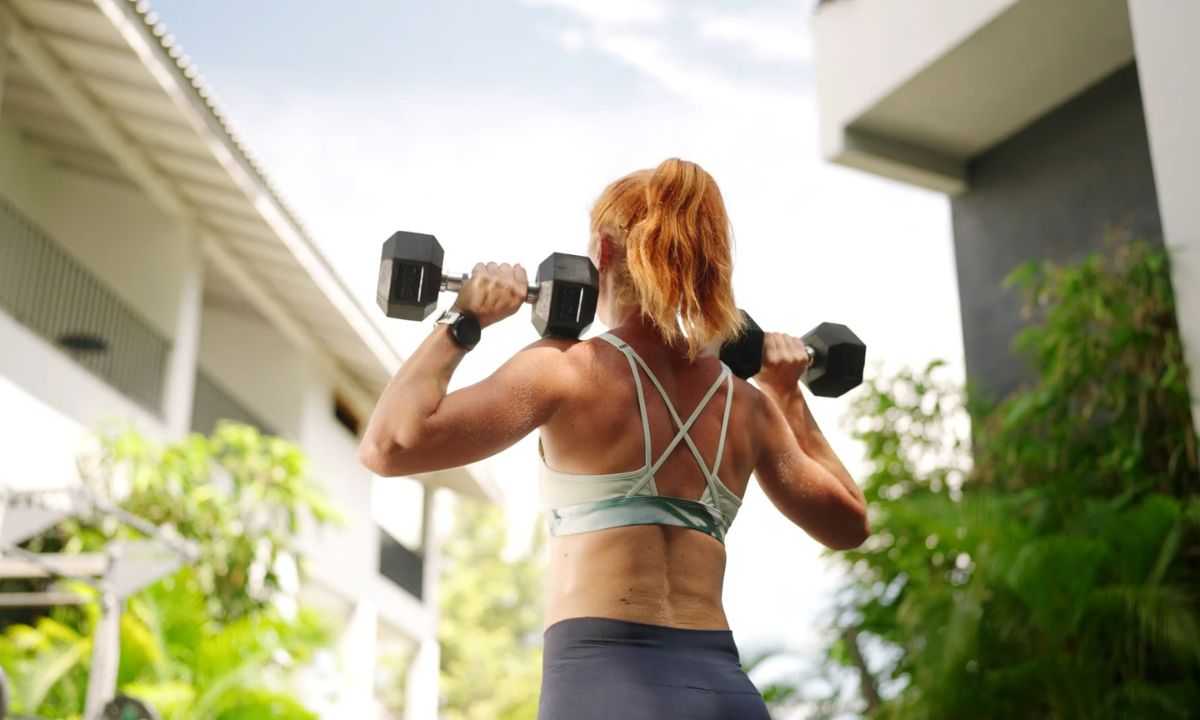 devojka u sportskom topu i helankama podiže tegove