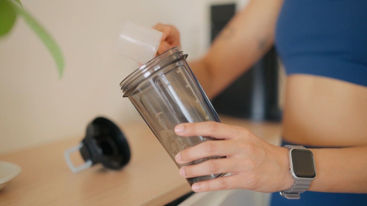 Žena sipa whey protein u šejker posle treninga