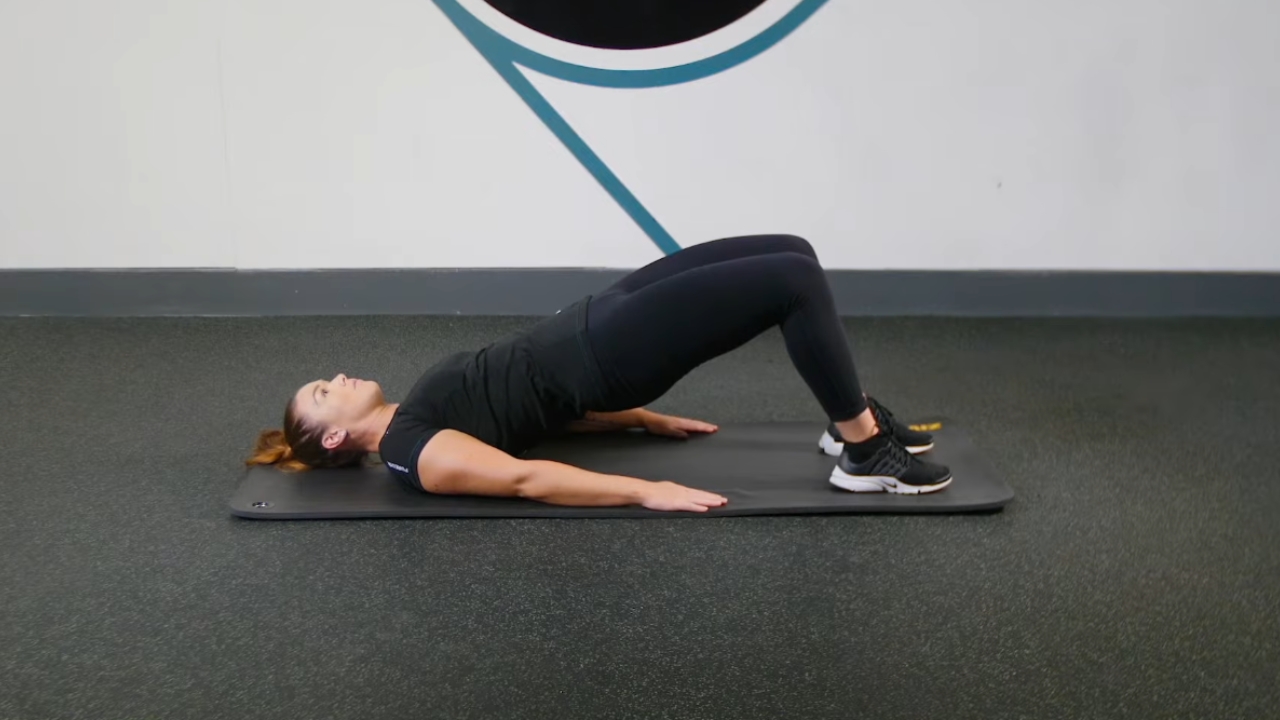 Žena na prostirci radi glute bridge vežbu za zadnjicu